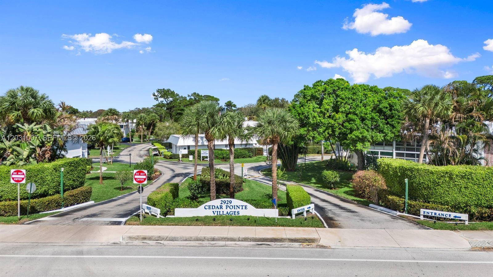 The entrance to a residential community features a sign, palm trees, and two paved driveways — 2929 SE Ocean Blvd # F6, Stuart FL 34996, STUART, FL