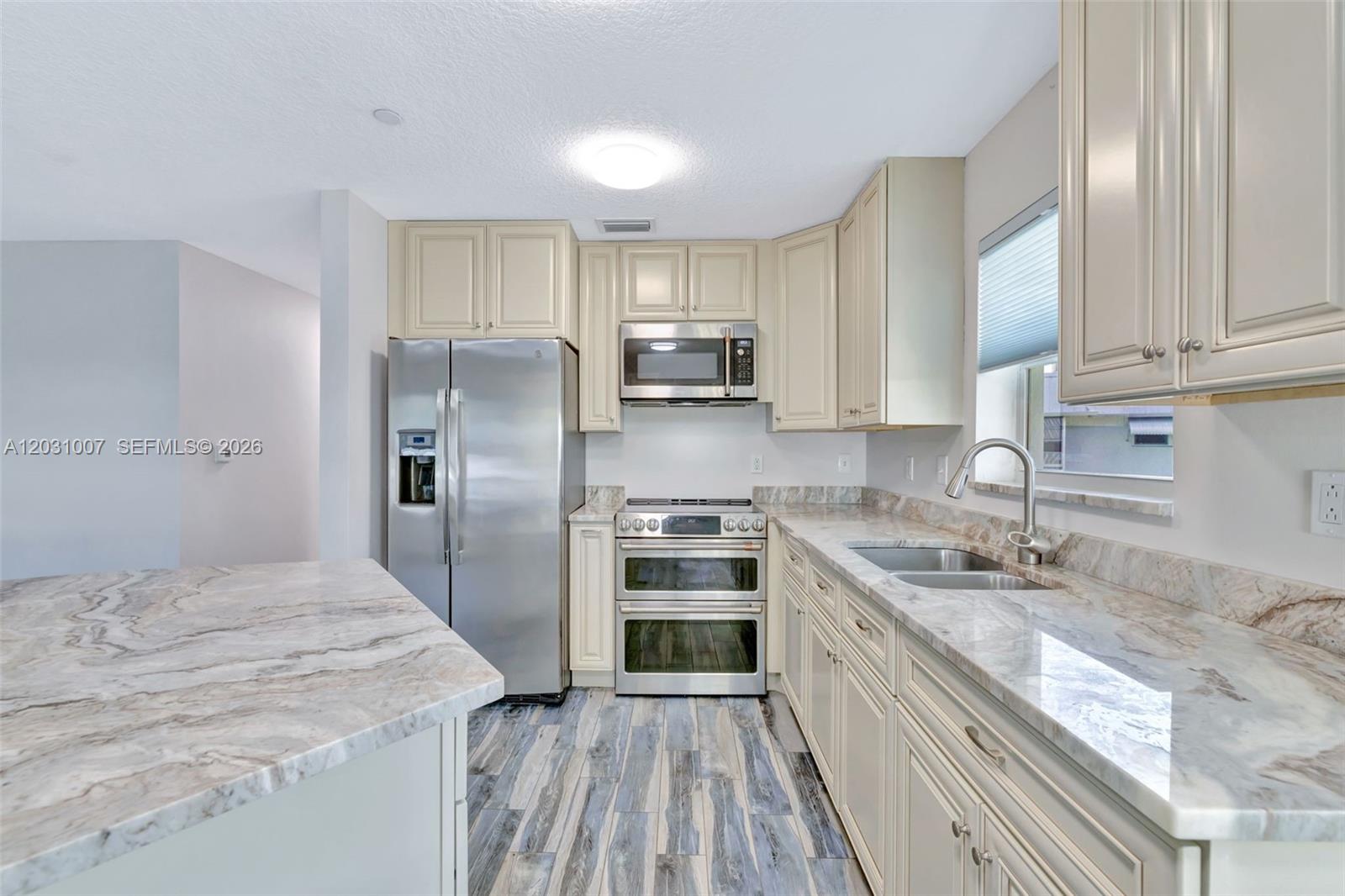 A kitchen features stainless steel appliances, light-colored cabinetry, and marble-patterned countertops — 2929 SE Ocean Blvd # F6, Stuart FL 34996, STUART, FL