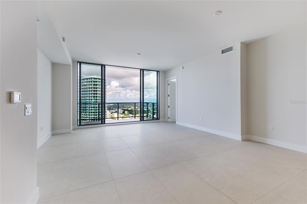 An empty room with light tile floors, white walls, and floor-to-ceiling windows overlooking a city — 275 1ST AVENUE S UNIT 3908, ST PETERSBURG, FL