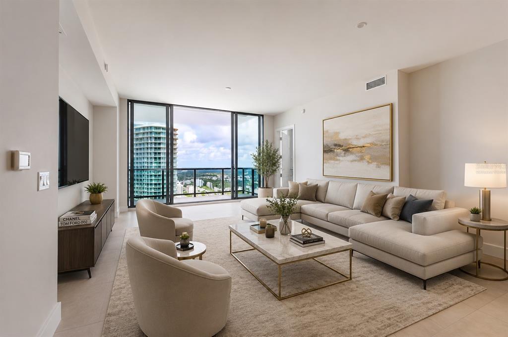 A modern living room features a sectional sofa, two armchairs, and a balcony with city views — 275 1ST AVENUE S UNIT 3908, ST PETERSBURG, FL