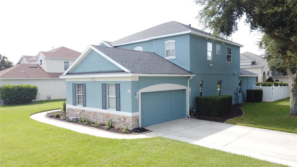 An exterior view of a two-story blue house with a stone-accented garage and driveway — 2705 KNIGHTSBRIDGE ROAD, CLERMONT, FL