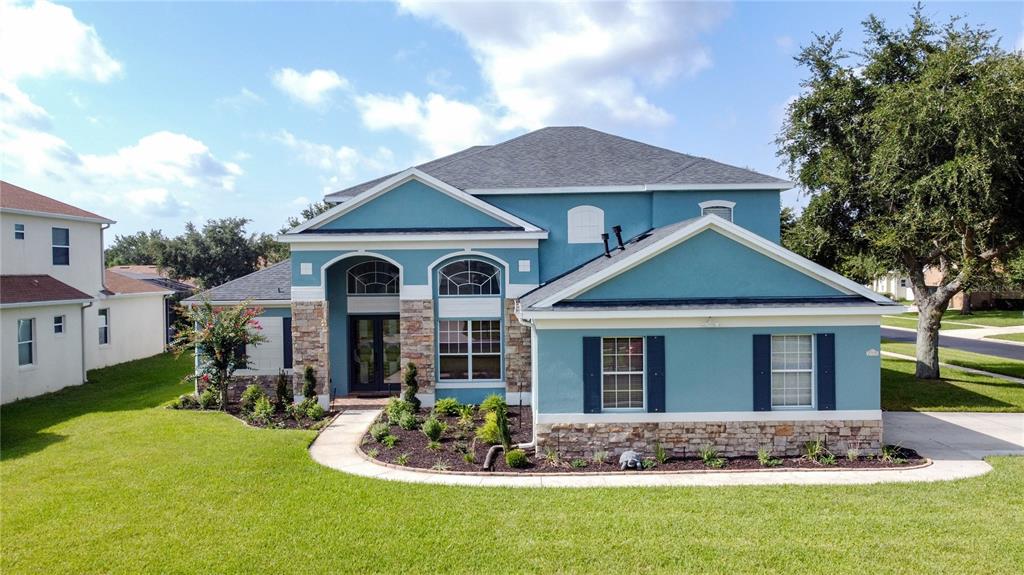 A two-story blue house with stone accents and a front walkway sits on a lawn — 2705 KNIGHTSBRIDGE ROAD, CLERMONT, FL