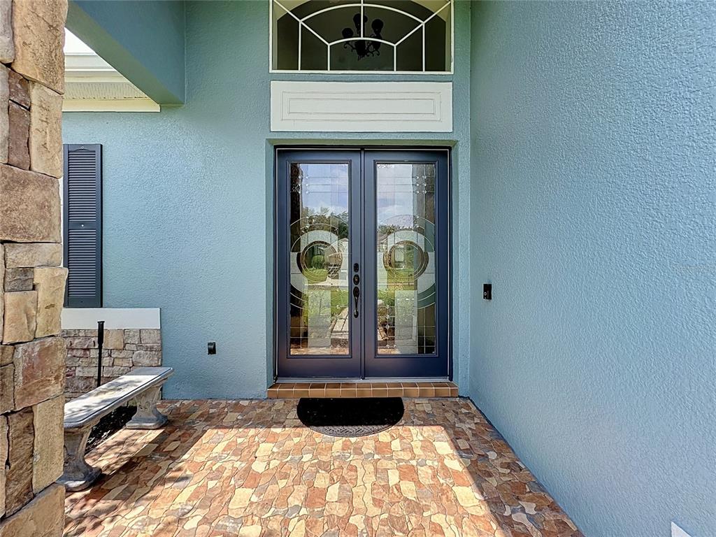 A front entryway features double glass doors, a stone-tiled porch, and a light blue exterior — 2705 KNIGHTSBRIDGE ROAD, CLERMONT, FL