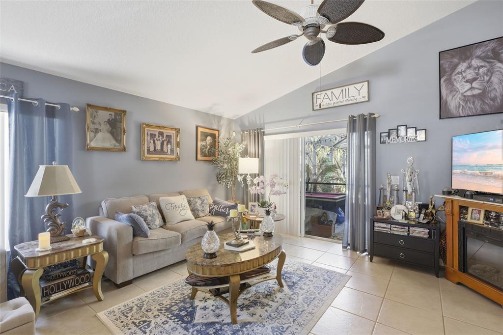A living room features a beige sofa, a patterned area rug, and a ceiling fan — 2848 DOE RUN TRAIL, ORANGE CITY, FL