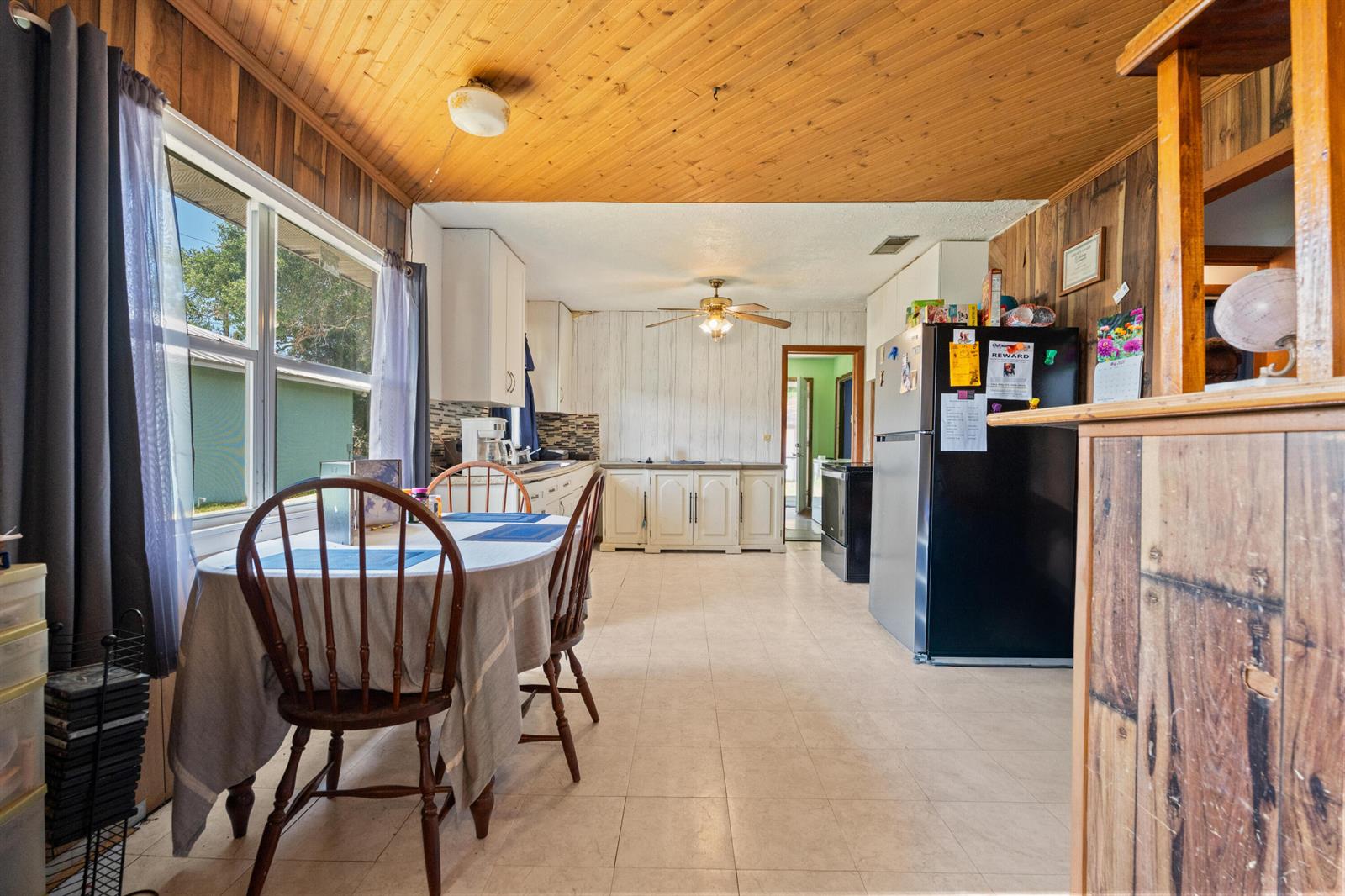 A kitchen and dining area with wood-paneled ceilings, tile flooring, and a black refrigerator — 1804 S 30th S, Fort Pierce FL 34947, FORT PIERCE, FL