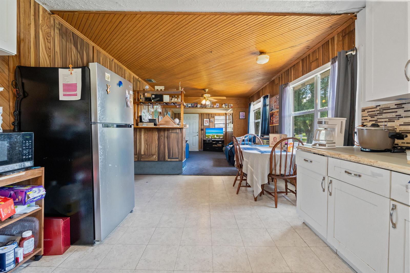 A kitchen with wood-paneled walls and ceiling opens into a dining area and living room — 1804 S 30th S, Fort Pierce FL 34947, FORT PIERCE, FL