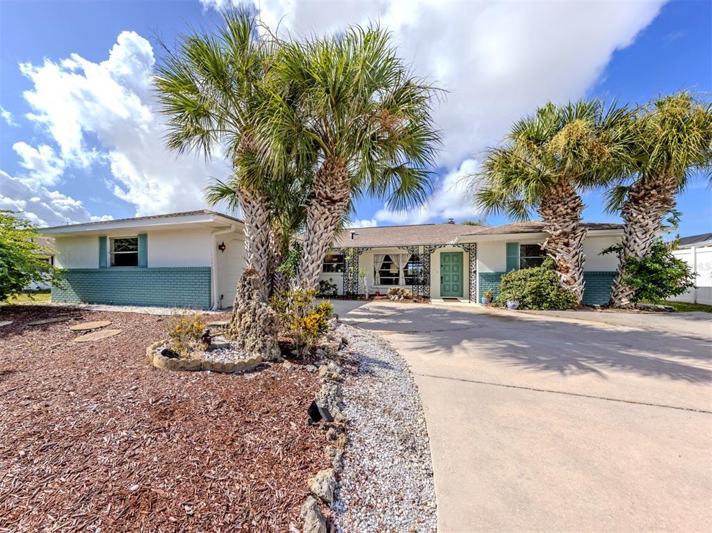 A single-story house with a teal brick facade, palm trees, and a concrete driveway — 1480 LAKESIDE DRIVE, VENICE, FL