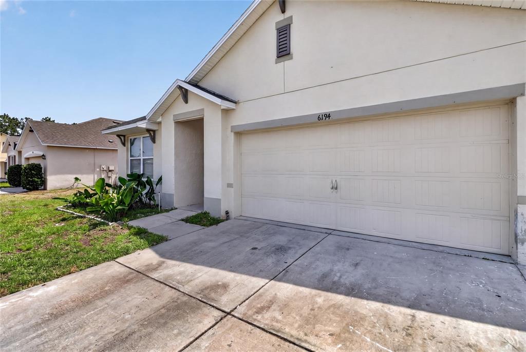 A beige single-story house features a two-car garage and a concrete driveway — 6194 GREY HERON DRIVE, WINTER HAVEN, FL
