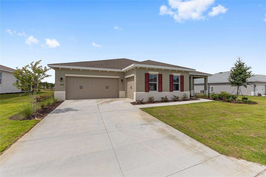 A single-story house with a tan exterior, red shutters, and a concrete driveway — 10618 SW 101ST LANE ROAD, OCALA, FL