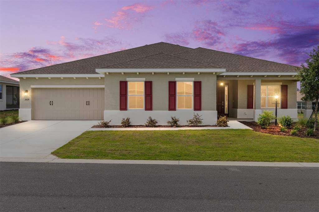 A single-story house with a beige stucco exterior, red shutters, and a two-car garage — 10618 SW 101ST LANE ROAD, OCALA, FL