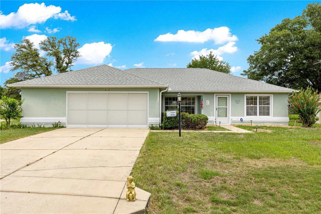 A single-story house with a light green exterior, a two-car garage, and a concrete driveway — 6185 SW 84TH STREET, OCALA, FL