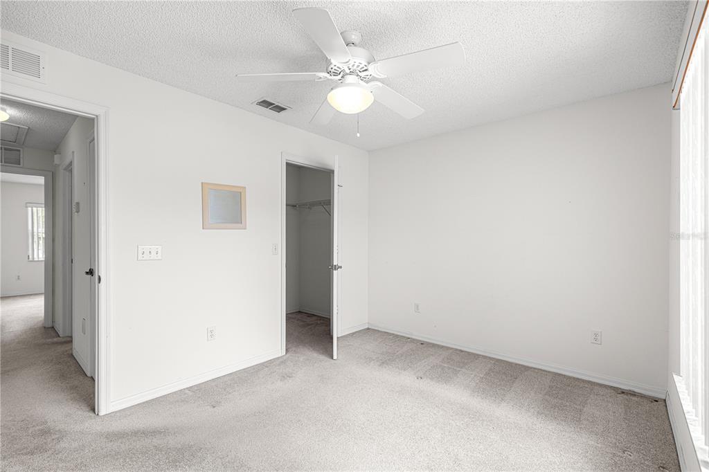 An empty bedroom with white walls, gray carpet, a ceiling fan, and an open closet — 6185 SW 84TH STREET, OCALA, FL