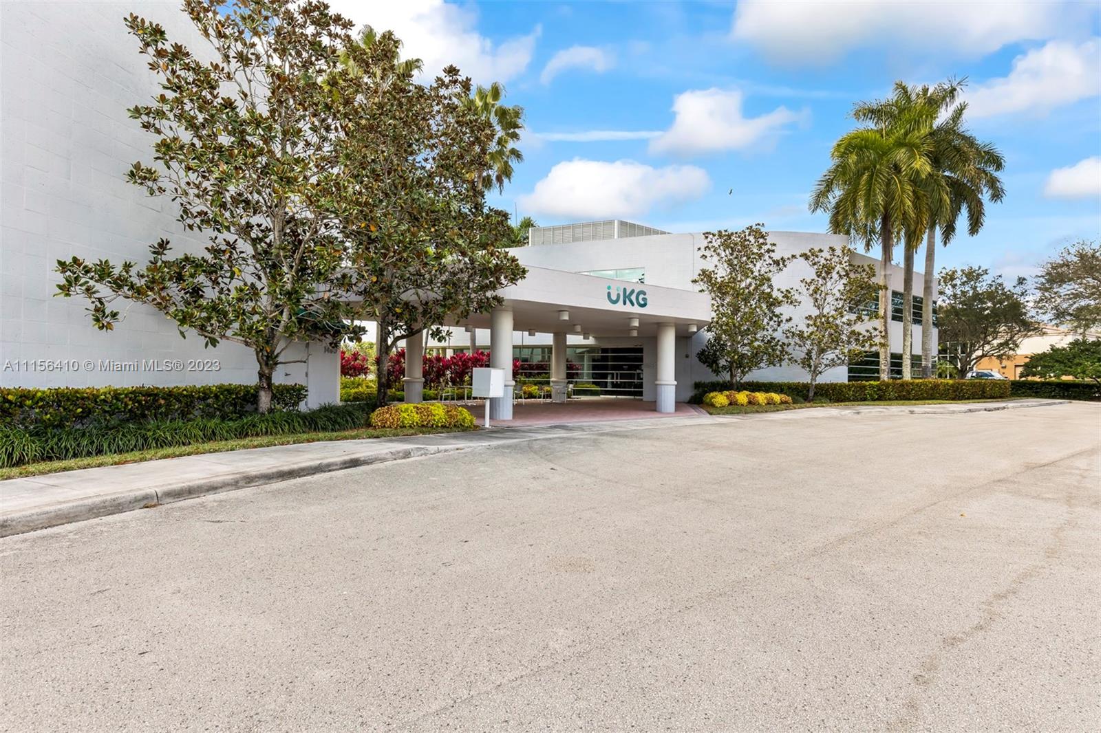 A white commercial building features a covered entrance with the UKG logo and palm trees — 1455 N Park Dr, Weston FL 33326, WESTON, FL