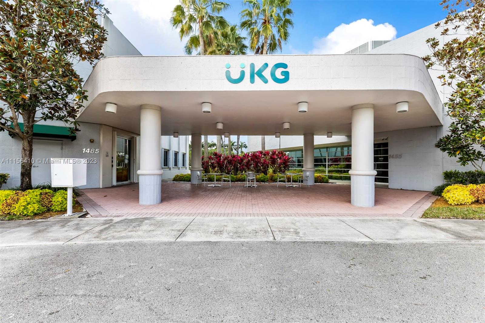 The exterior of a commercial building features a covered entrance with a large UKG sign — 1455 N Park Dr, Weston FL 33326, WESTON, FL