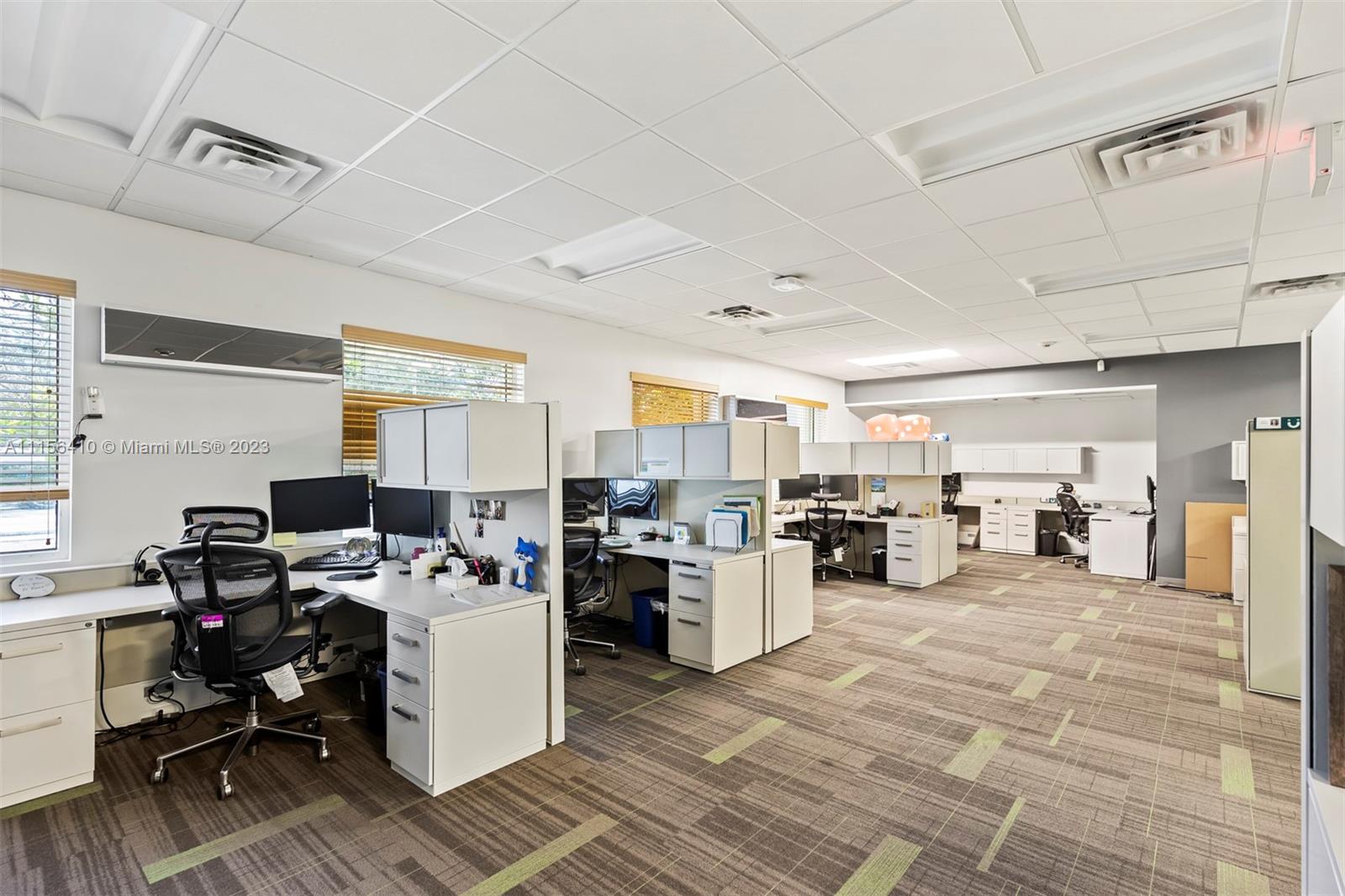 An office space features multiple cubicle workstations, white desks, rolling chairs, and patterned carpet flooring — 1455 N Park Dr, Weston FL 33326, WESTON, FL