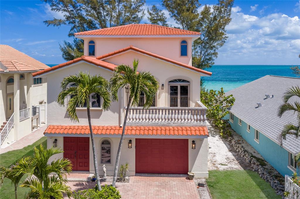 A two-story stucco house with a red tile roof, red garage door, and ocean view — 889 N SHORE DRIVE, ANNA MARIA, FL