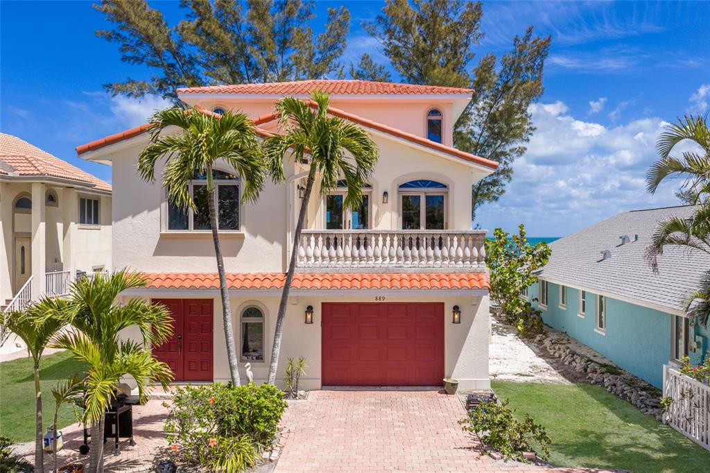 A two-story stucco house with a red tile roof, red garage door, and palm trees — 889 N SHORE DRIVE, ANNA MARIA, FL