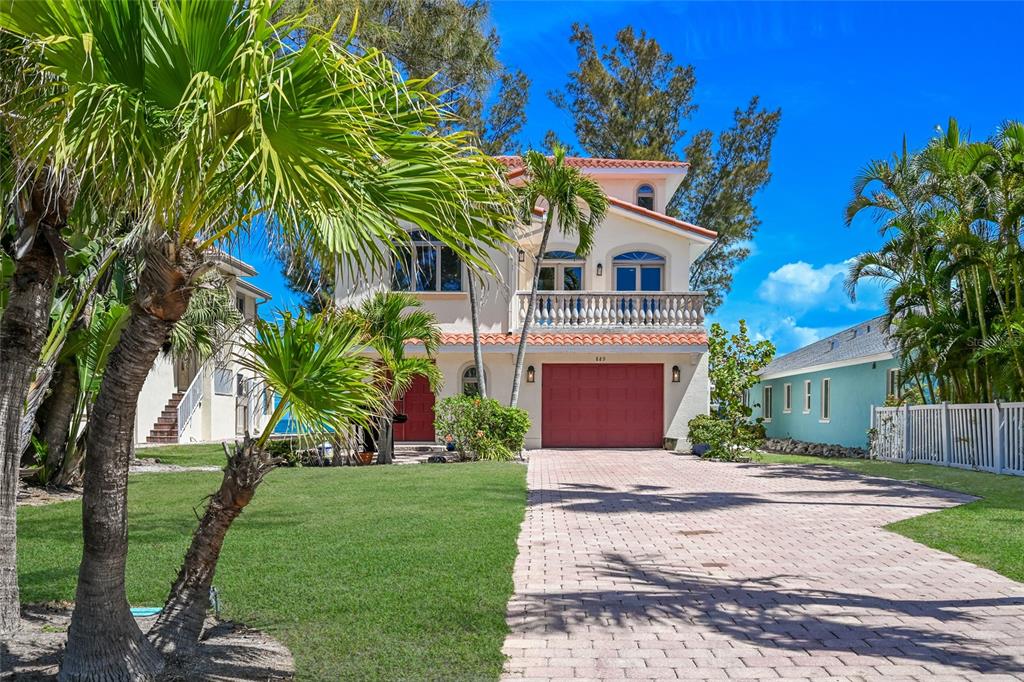 A two-story house with a red garage door, a balcony, and a paved driveway — 889 N SHORE DRIVE, ANNA MARIA, FL