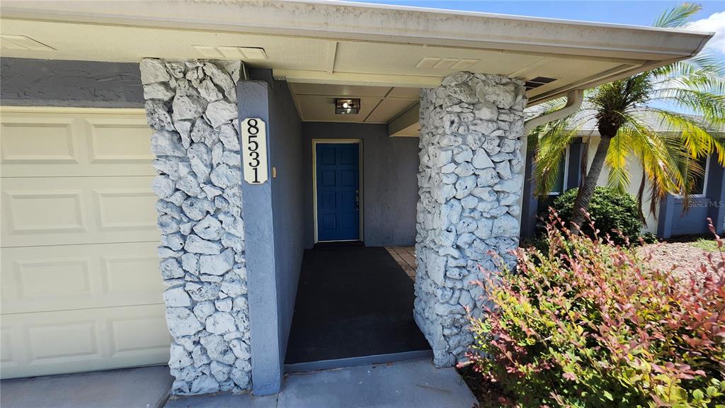 The exterior of a house features a blue front door and white stone columns — 8531 PORT SAID STREET, ORLANDO, FL