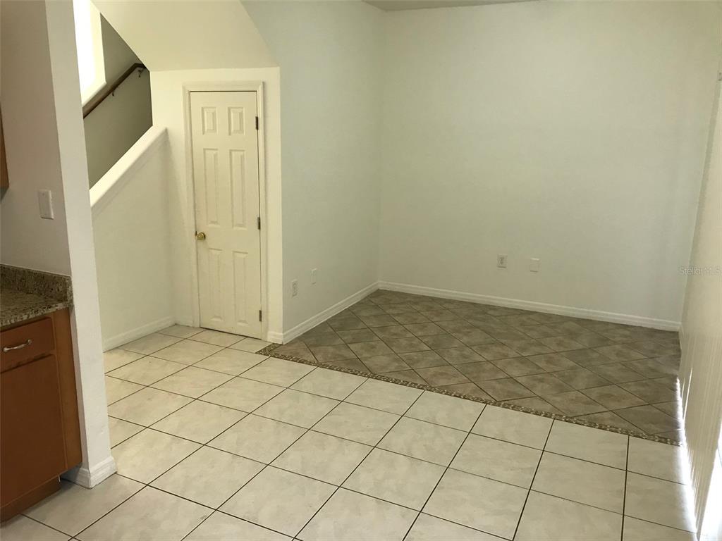 A dining area features diagonal tile flooring, a white door, and a staircase nearby — 7635 PLANTATION CIRCLE UNIT 7635, BRADENTON, FL