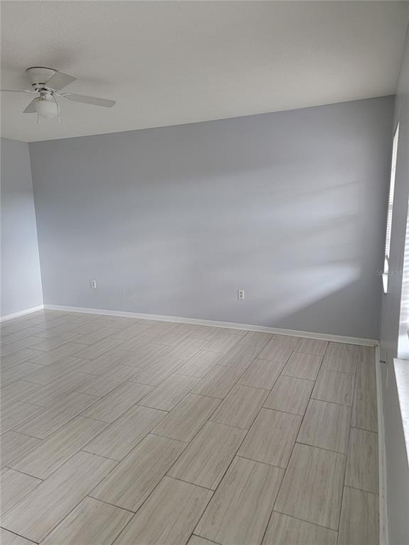 An empty room features light gray walls, a ceiling fan, and wood-look tile flooring — 2621 SW 33 AVENUE, OCALA, FL