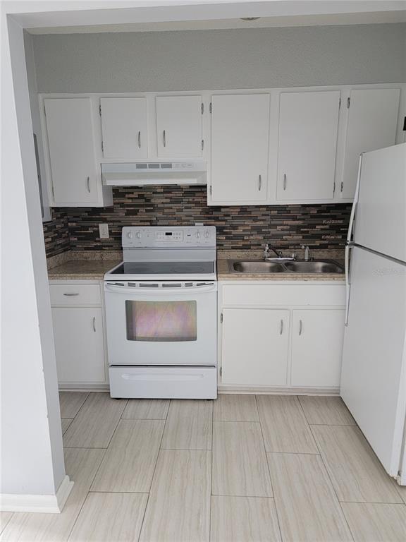 A kitchen with white cabinets, a white stove, a double sink, and a tiled backsplash — 2621 SW 33 AVENUE, OCALA, FL