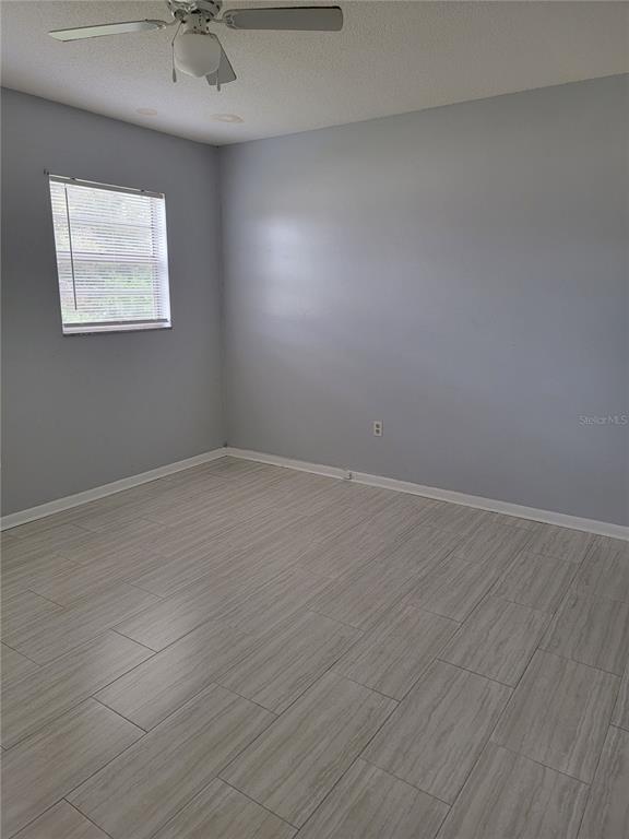 An empty room features light gray walls, wood-look tile flooring, and a ceiling fan — 2621 SW 33 AVENUE, OCALA, FL