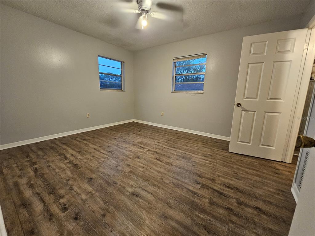 An empty bedroom features gray walls, wood-look flooring, two windows, and a white door — 2621 SW 33 AVENUE, OCALA, FL