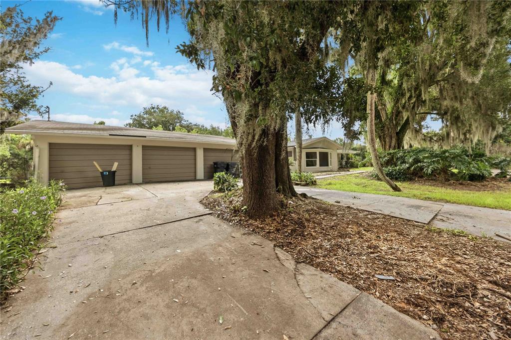 A detached three-car garage sits next to a house surrounded by large, moss-draped oak trees — 5430 TIMBERLANE ROAD, LAKE WALES, FL