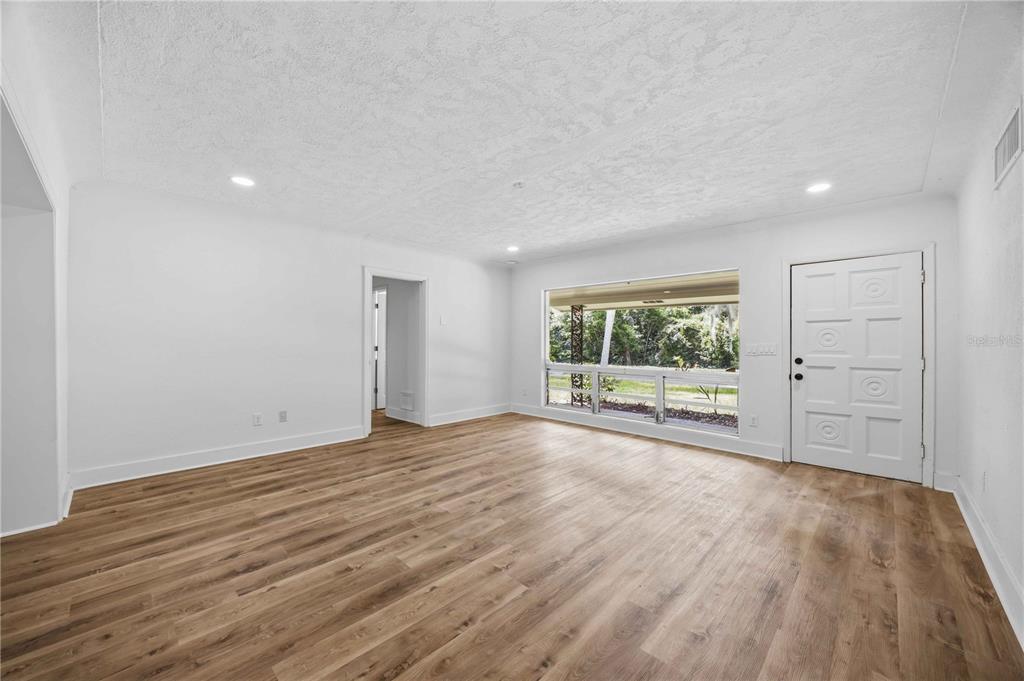An empty room with light wood-look flooring, white walls, recessed lighting, and a large window — 5430 TIMBERLANE ROAD, LAKE WALES, FL