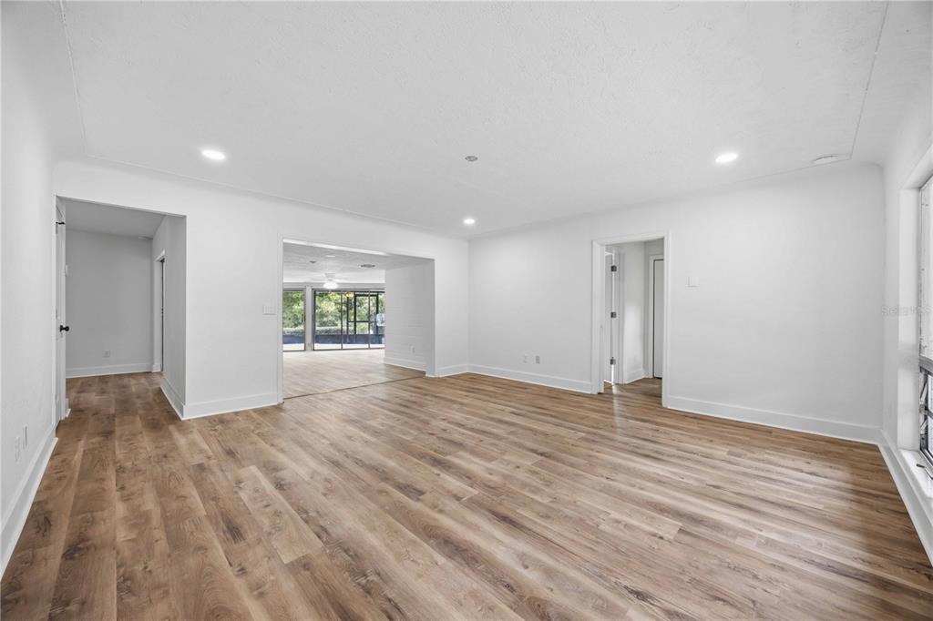 A bright, empty room features white walls, recessed lighting, and light wood-look flooring — 5430 TIMBERLANE ROAD, LAKE WALES, FL