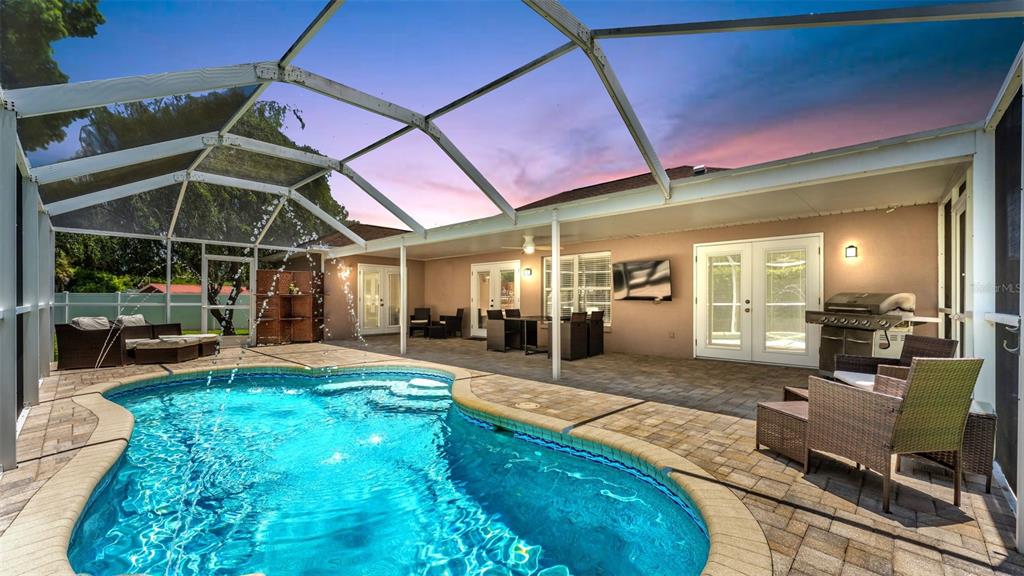 A screened-in patio features a swimming pool with a fountain and outdoor seating area — 2219 TOWERING OAKS CIRCLE, SEFFNER, FL
