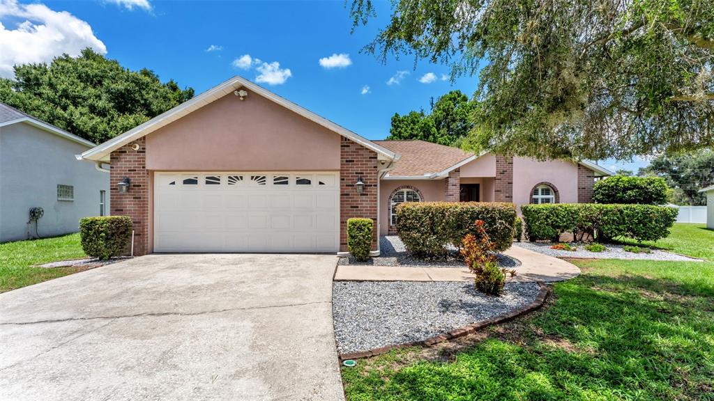 A single-story house with a two-car garage, brick facade, and a gravel front yard — 2219 TOWERING OAKS CIRCLE, SEFFNER, FL