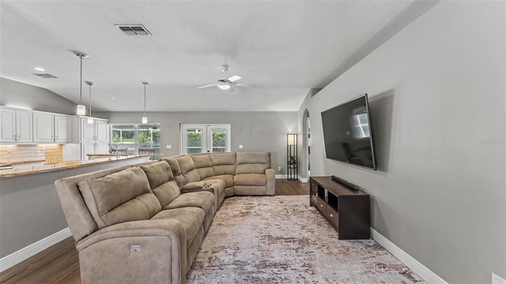 A living room features a large sectional sofa, a wall-mounted television, and an open kitchen — 2219 TOWERING OAKS CIRCLE, SEFFNER, FL