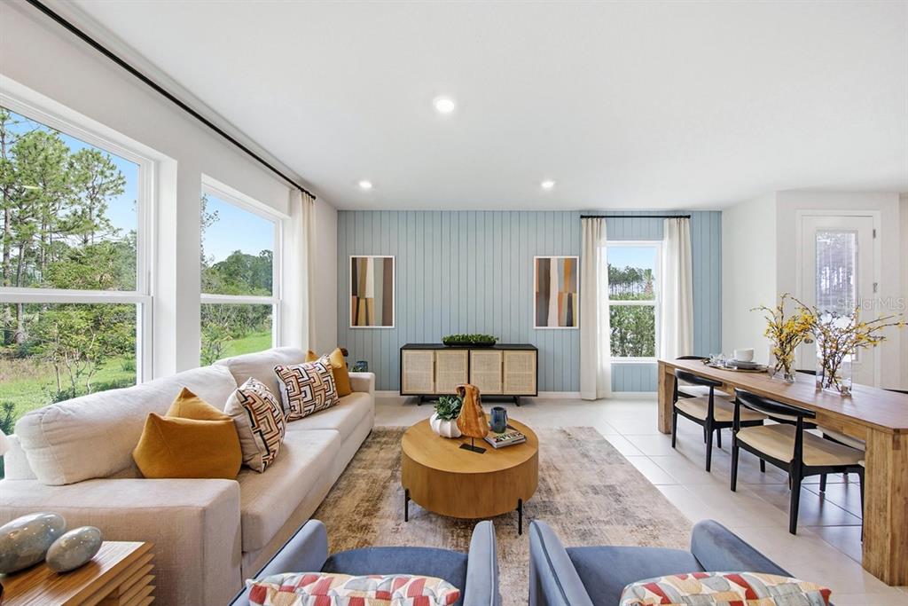 A living and dining area features a light blue paneled wall, wood furniture, and large windows — 1132 WILD CREST LANE, DAYTONA BEACH, FL