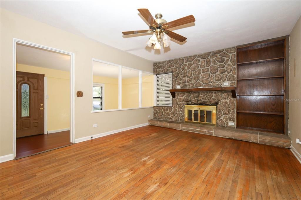 A living room features hardwood floors, a stone fireplace, and built-in wooden shelving — 921 ELDRIDGE STREET, ORLANDO, FL
