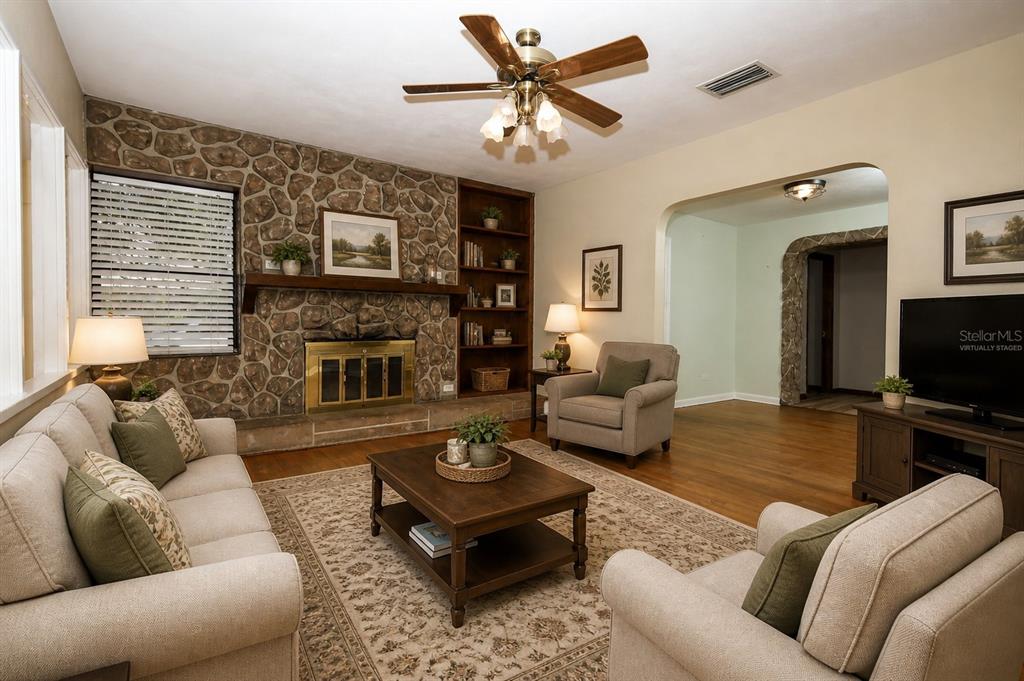 A living room features a stone fireplace, built-in shelving, a ceiling fan, and hardwood floors — 921 ELDRIDGE STREET, ORLANDO, FL