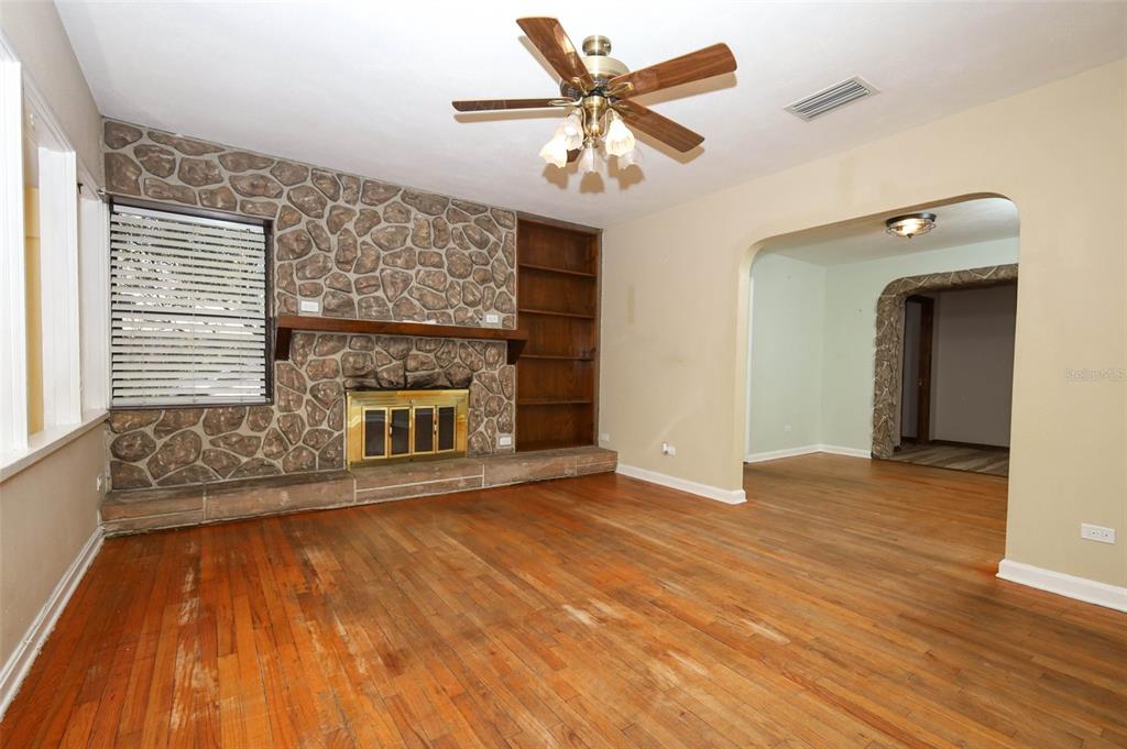 A living room features a stone fireplace, built-in shelving, hardwood floors, and a ceiling fan — 921 ELDRIDGE STREET, ORLANDO, FL