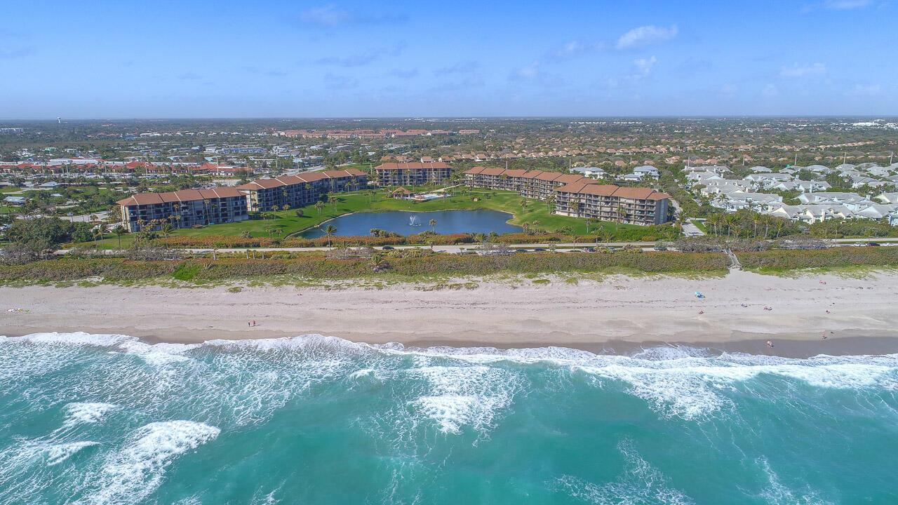 An aerial view shows two multi-story apartment buildings situated beside a lake and beach — 301 S Seas Drive # 305, Jupiter FL 33477, JUPITER, FL