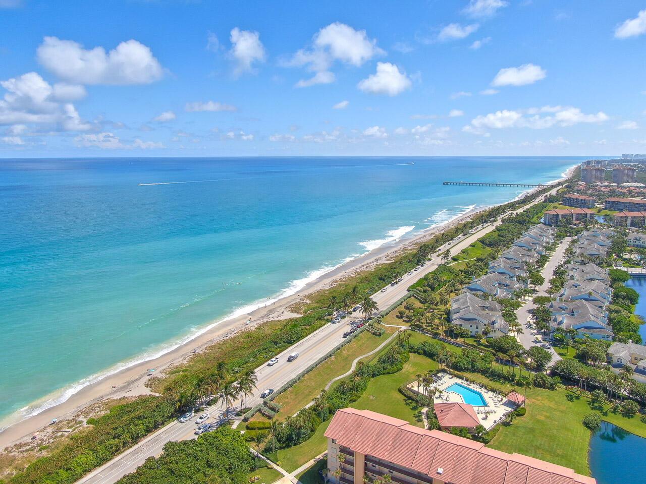 An aerial view of a coastal road running alongside a beach with residential buildings nearby — 301 S Seas Drive # 305, Jupiter FL 33477, JUPITER, FL