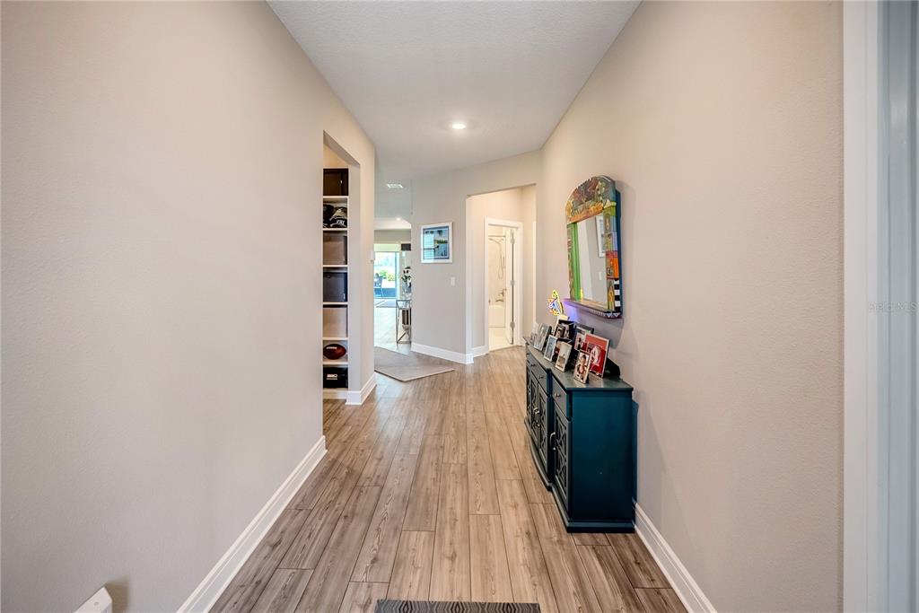 A hallway with wood-look flooring, a blue console table, and a built-in shelving unit — 9435 SW 52ND LOOP, OCALA, FL