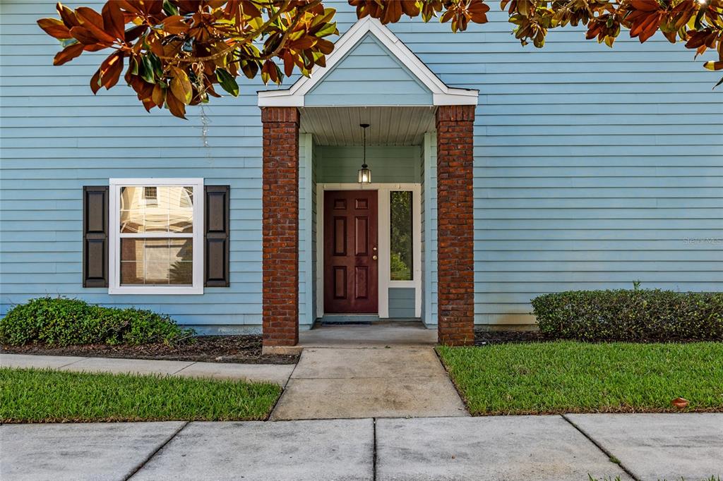 The exterior of a light blue house features a brick-columned entryway and a dark door — 10545 NW 30TH LANE, GAINESVILLE, FL