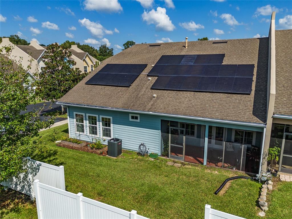 A rear view of a house with solar panels on the roof and a fenced yard — 10545 NW 30TH LANE, GAINESVILLE, FL
