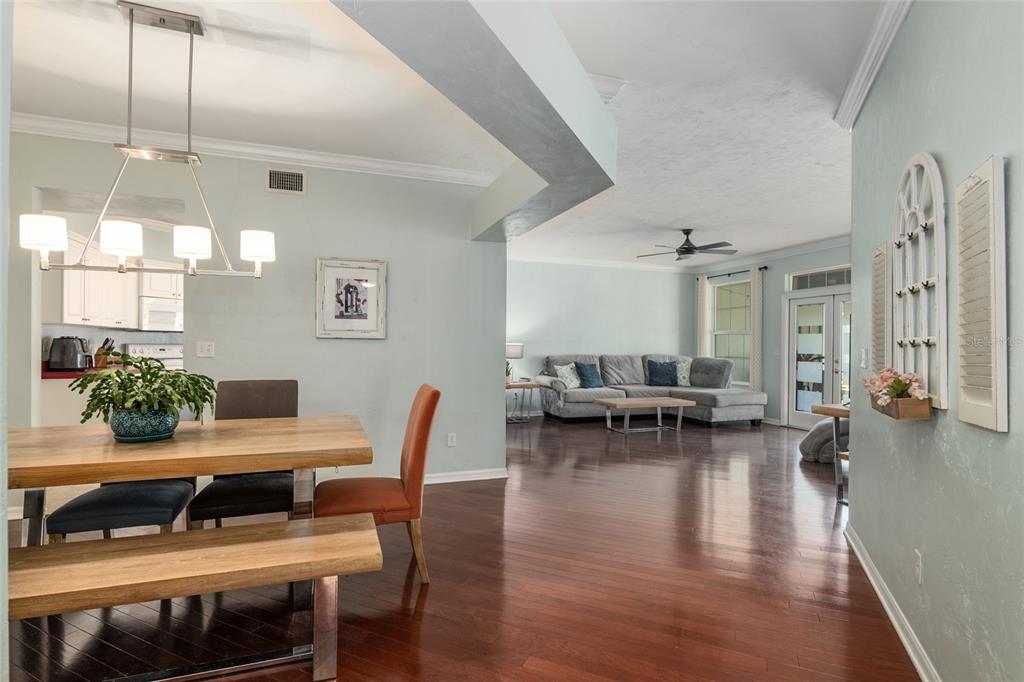 A dining area with a wooden table and bench opens into a spacious living room — 10545 NW 30TH LANE, GAINESVILLE, FL
