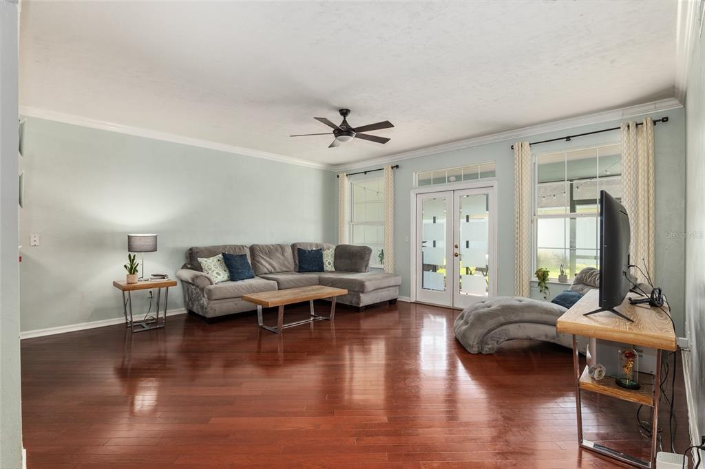 A living room features light blue walls, dark hardwood floors, a sectional sofa, and a television — 10545 NW 30TH LANE, GAINESVILLE, FL