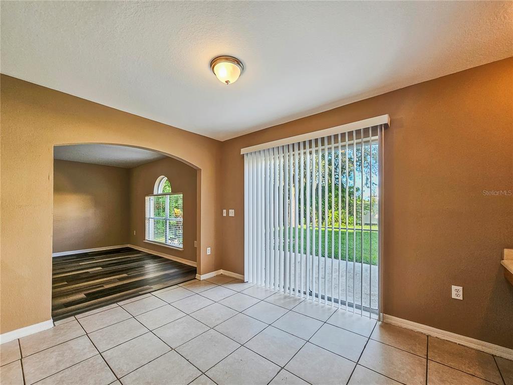 A dining area with tile flooring, tan walls, and a sliding glass door to the backyard — 3650 FYFIELD COURT, LAND O LAKES, FL