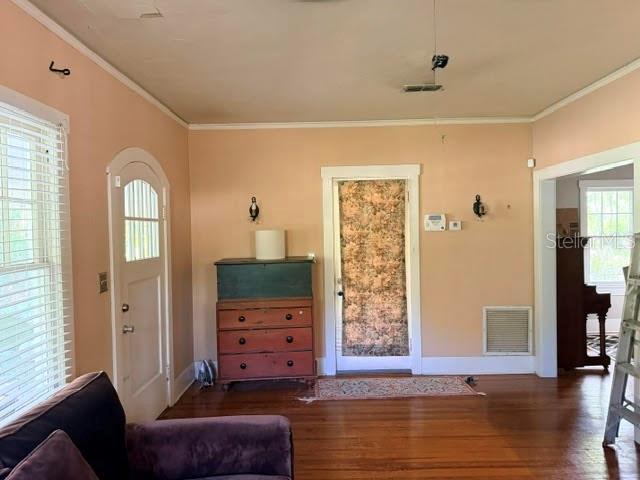 A living room with hardwood floors, a wooden dresser, and two doorways leading to other rooms — 1255 SE SILVER SPRINGS PLACE, OCALA, FL