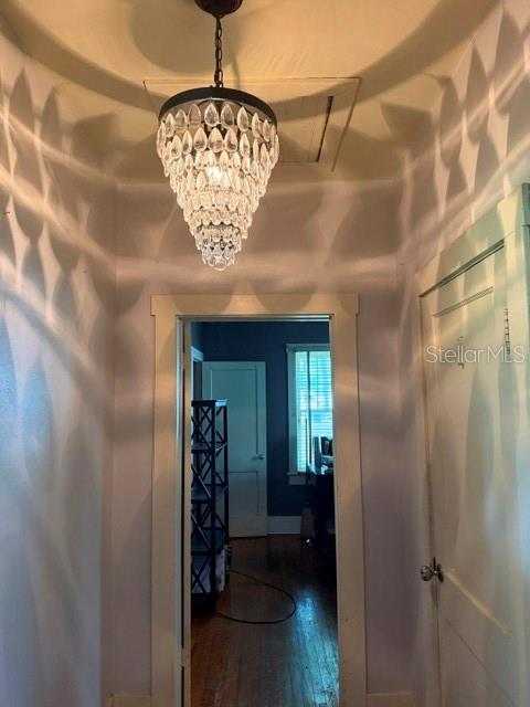 A hallway with a crystal chandelier leads to a room with dark walls and wood floors — 1255 SE SILVER SPRINGS PLACE, OCALA, FL