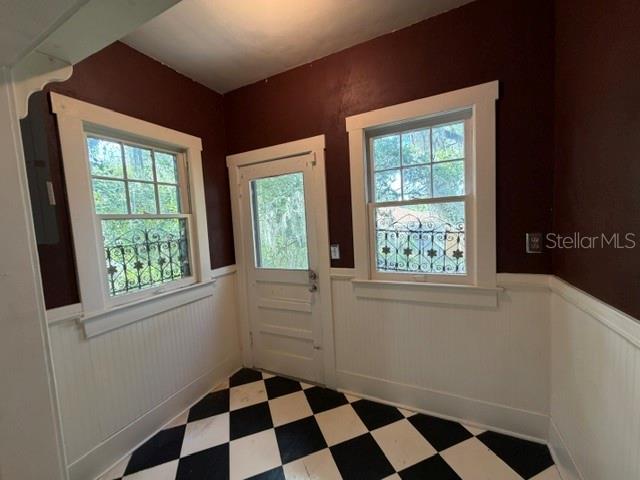 A sunroom with white wainscoting, dark walls, two windows, and a black-and-white checkered floor — 1255 SE SILVER SPRINGS PLACE, OCALA, FL