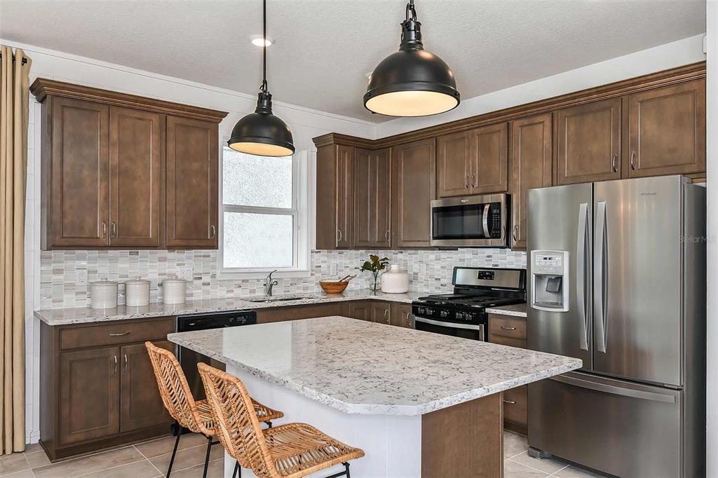 A kitchen features dark wood cabinets, granite countertops, stainless steel appliances, and a central island — 2621 HAMMOCK HARBOR AVENUE, ST CLOUD, FL